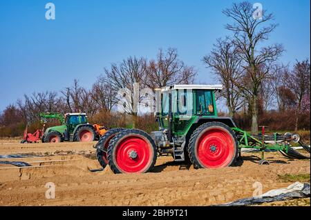 Brandenburg, Deutschland - 28. März 2020: Blick auf Traktoren und Maschinen, die bereit sind, in Deutschland ein Spargelfeld für den Anbau vorzubereiten. Stockfoto