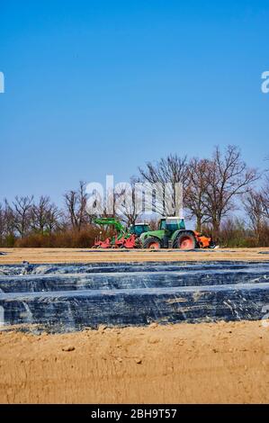 Brandenburg, Deutschland - 28. März 2020: Blick auf Traktoren und Maschinen, die bereit sind, in Deutschland ein Spargelfeld für den Anbau vorzubereiten. Stockfoto