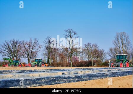 Brandenburg, Deutschland - 28. März 2020: Blick auf Traktoren und Maschinen, die bereit sind, in Deutschland ein Spargelfeld für den Anbau vorzubereiten. Stockfoto