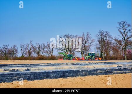 Brandenburg, Deutschland - 28. März 2020: Blick auf Traktoren und Maschinen, die bereit sind, in Deutschland ein Spargelfeld für den Anbau vorzubereiten. Stockfoto