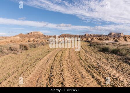 Roadtrip im Winter durch die Halbwüste Bardenas Reales, Navarra, Spanien. Ein UNESCO Biosphärenreservat mit u.a. Castil de Tierra, Pisquerra Mountains und Bardena Blanca. Schotterstraße. Stockfoto