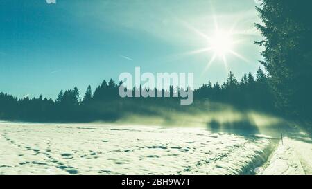 Schneebedeckte Landschaft im Murnauer Moos mit Blick auf die Gipfel der Alpen. Stockfoto