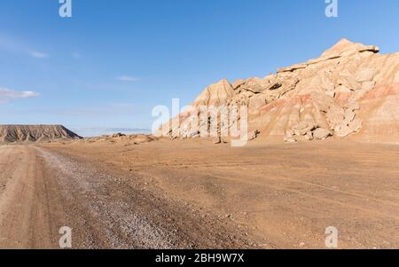 Roadtrip im Winter durch die Halbwüste Bardenas Reales, Navarra, Spanien. Ein UNESCO Biosphärenreservat mit u.a. Castil de Tierra, Pisquerra Mountains und Bardena Blanca. Schotterstraße. Stockfoto