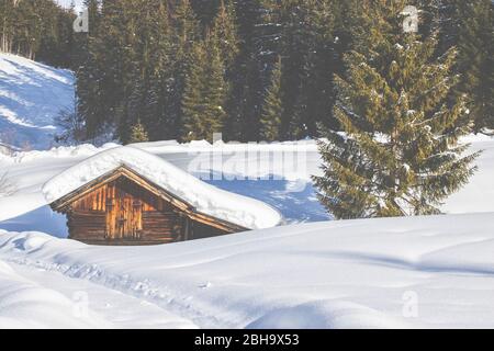 Eine schneebedeckte Hütte am Tennsee bei Krün im Winter mit Blick auf das Wettersteinmassiv und die Gipfel der Alpen im Landkreis Garmisch-Partenkirchen, Bayern, Deutschland. Stockfoto