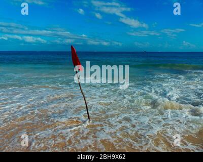 Eine rote Flagge, die vom Rettungsschwimmer angebracht wird, weist auf eine Gefahr hin. Keine Schwimmer dürfen ins Wasser. Stockfoto