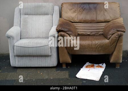 Zwei couch Stühle stehen auf einem Bürgersteig mit Essensreste von Obdachlosen. Stockfoto