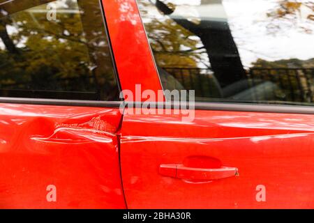 Tür rotes Auto bei einem tiefen Dellen Unfall beschädigt, Kratzer an den Türen. Konzept der Autoreparatur. Stockfoto