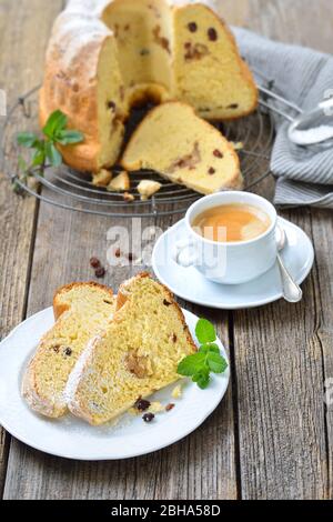 Frischer österreichischer Heferingkuchen mit Mandelpaste und Rosinen, sogenannter Gugelhupf, serviert mit einer Tasse köstlichem Kaffee Crema Stockfoto