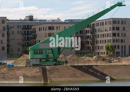 Eine alte Hafenkran für kleinere Schiffe am Ufer des einen Binnenhafen von neuen Wohnsiedlungen in Mainz. Stockfoto