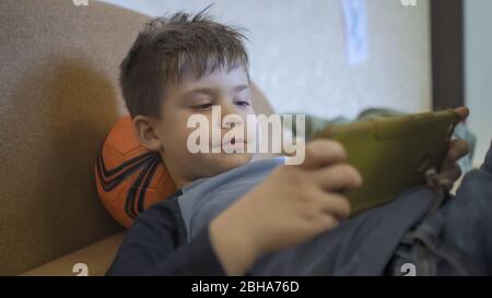 Boy Spielt Auf Handy Auf Sofa Liegen Stockfoto