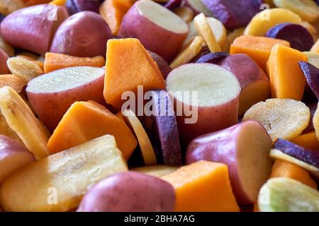 Gehackte Kartoffeln, Kürbisse und orange, gelbe und lila Karotten. Flacher Einschnitt von frisch geschnittenem Gemüse in verschiedenen Farben. Gesundes Essen Konzept. Stockfoto