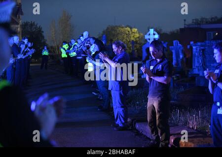 Swansea, Wales, Großbritannien. April 2020. Die Mitarbeiter des Rettungsdienstes stehen zu Ehren in einer Wache, die von einer Flut von blauem Licht aus ihren Fahrzeugen überflutet wird, während eines Gedenkens für den Rettungsdienst Gerallt Davies, der letzte Woche an Covid-19 gestorben ist. Die Mitarbeiter, viele, die mit Gerallt arbeiteten, wurden mit Mitgliedern seiner Gemeinde aus dem Dorf Pontadardawe in der Nähe von Swansea verbunden. Er war das erste Mitglied des Welsh Ambulance Services NHS Trust, das mit Covid-19 starb, so sein Chief Executive. Quelle : Robert Melen/Alamy Live News. Stockfoto