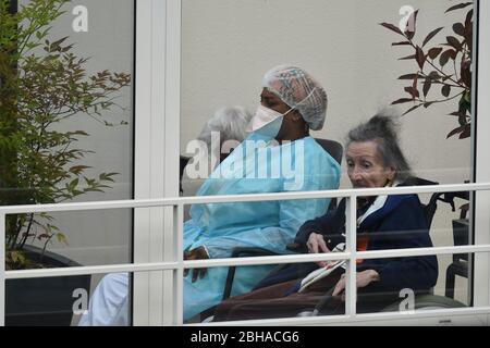 Krankenschwester Pflege für ältere Menschen in einem Pflegeheim während der Coronavirus-Pandemie Covid-19. Betreuerin mit zwei alten Frauen, die dort wohnen. Stockfoto