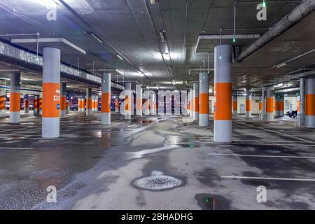 Asphaltierte, schwach beleuchtete leere Mall Garage mit Deckenleuchten. Stockfoto