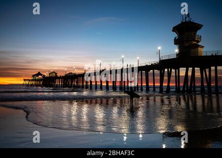 Silhouette des Surfers am Huntington Beach Pier bei Sonnenuntergang, Kalifornien, USA Stockfoto
