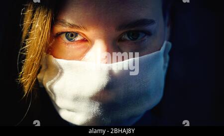 Augen einer Frau in einer Gaze-Maske, die die Kamera aus nächster Nähe anschaut. Vorbeugender Schutz Ihrer eigenen Gesundheit vor Virusinfektionen. Coronavirus-Konzept. Stockfoto