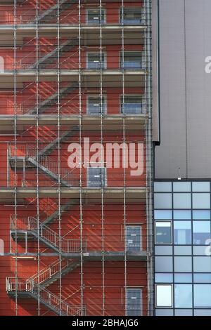 Die Außentreppe in ein Wohn- und Geschäftshaus wirft Schatten hinter Gittern. Stockfoto