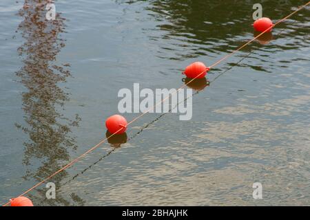 Ein gestrecktes Seil mit nebeneinander angeeinandergereisten schwimmenden Bojen, um einen Wasserzugang im Binnenhafen abzusperren. Stockfoto