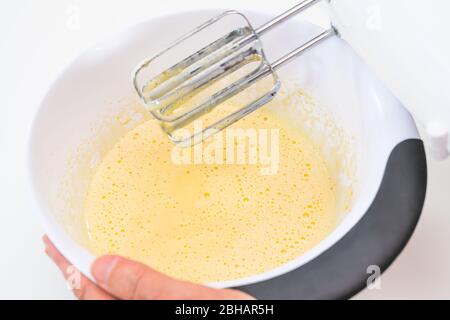 Mischen von Keksteig mit einem elektrischen Mixer. Nahaufnahme Prozess. Kuchen Teig machen. Stockfoto