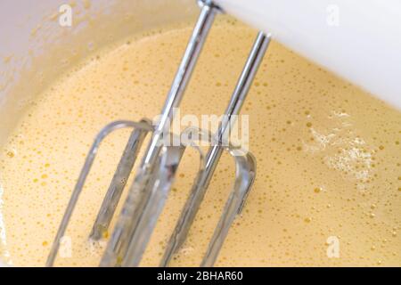 Mischen von Keksteig mit einem elektrischen Mixer. Nahaufnahme Prozess. Kuchen Teig machen. Stockfoto