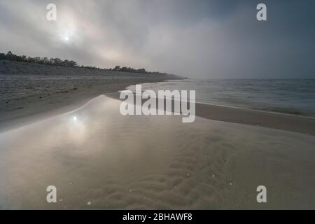 Sonnenaufgang im Winter am Meer mit einem fallenden Nebel von heller Sonne an einem schönen Wintertag Stockfoto