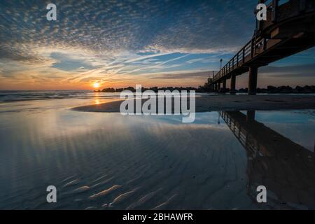 Ostsee im strahlenden Gegenlicht mit dem Pier in Wustrow und Spiegelung der schönen Wolken am Strand Stockfoto