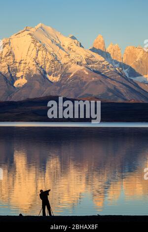 Fotograf (Model veröffentlicht) bei Sonnenaufgang am Rande des Lago Sarimento in Torres del Paine, in chilenischem Patagonien Stockfoto