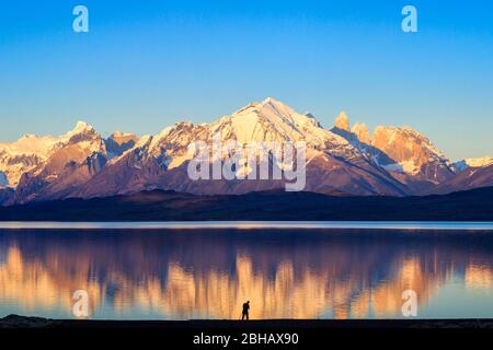 Fotograf (Model veröffentlicht) bei Sonnenaufgang am Rande des Lago Sarimento in Torres del Paine, in chilenischem Patagonien Stockfoto