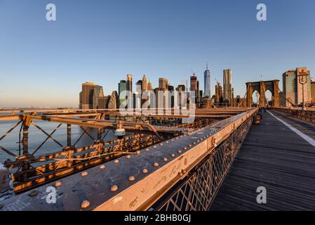 Blick über die verlassene Brooklyn Bridge zur Silhouette der Innenstadt von Manhattan bei Sonnenaufgang im Sommer Stockfoto