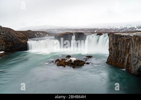 Berühmter godafoss Wasserfall in island im Frühling mit schneebedeckten Bergen Stockfoto