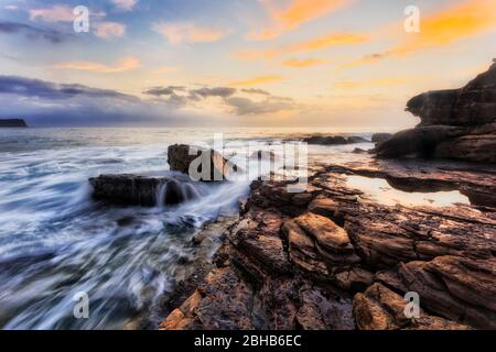 Sandsteinfelsen mit Gezeiten Salzwasser-Pibble bei Sonnenaufgang nach Osten auf Sydney Northern Beaches und Pacific Coast. Stockfoto