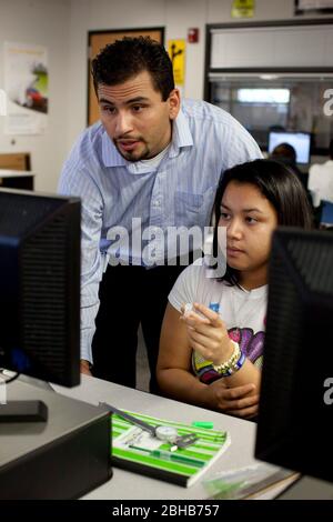 Carrollton Texas USA, Mai 18 2010: Der hispanische Lehrer blickt auf die Arbeit einer hispanischen Schülerin an einem Computer im Klassenzimmer der METSA High School. ©Bob Daemmrich Stockfoto