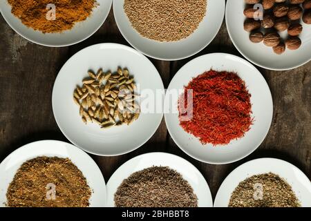 Verschiedene Gewürze auf Tellern, auf altem Holztisch Stockfoto