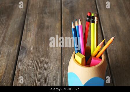 Bunte Bleistifte in Halter mit Haftnotizen auf Holzplanken Hintergrund Stockfoto