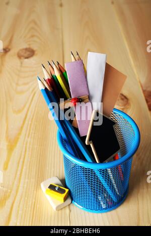 Bleistifte und Papiernotizen in Metallhalter und Holzschreibtischuntergrund Stockfoto