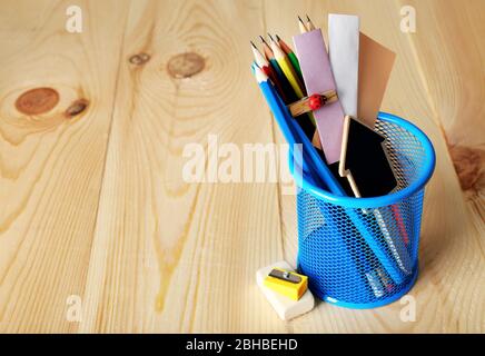 Bleistifte und Papiernotizen in Metallhalter und Holzschreibtischuntergrund Stockfoto