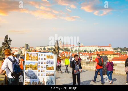 Die St.-Veits-Kathedrale und der Schlosskomplex im Blick, wenn Touristen an Straßenkünstlern und Statuen auf der Karlsbrücke in Prag, Tschechien vorbeikommen. Stockfoto