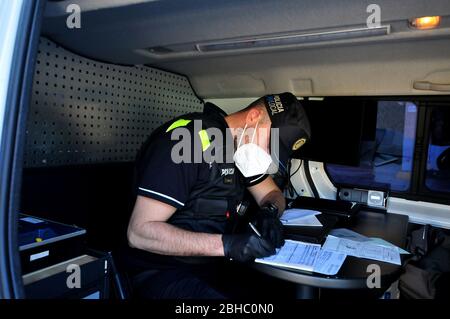 Vendrell, Spanien. April 2020. Ein Polizist gibt einem Fahrer eine Strafe, weil er die Haftbedingungen nicht eingehalten hat.Lokale Polizisten werden auf den Straßen von El Vendrell eingesetzt, um ungerechtfertigte Bewegungen von Bürgern aus anderen Städten zu patrouillieren und zu kontrollieren, die an einem Wochenende und bis zu ihren Zweitwohnungen gelangen Stellen Sie sicher, dass die Regeln für die Beschränkung eingehalten werden, um die Ausbreitung des COVID-19 Coronavirus zu kontrollieren. Quelle: SOPA Images Limited/Alamy Live News Stockfoto