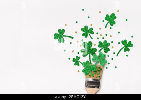 Kreatives St. Patricks Day Konzept. Pinsel mit grünen Glitzer Kleeblätter und Konfetti malen. Minimal St. Patricks Day Hintergrund. Stockfoto