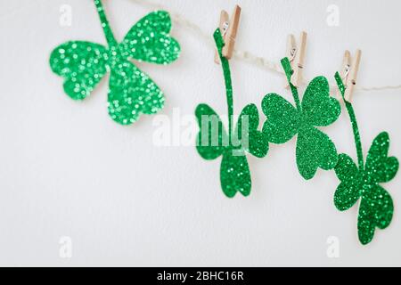 Alles gute zum St. Patricks Tag. Grüne Glitzer Kleeblätter Dekoration. Hausgemachte Girlande aus Seil und Kleeblätter auf Wäscheklammern. Stockfoto