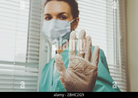 Der Arzt des Krankenpflegers zeigt die Geste Stop Coronavirus im Handschuh. Ende der Coronavirus-Epidemie. Stockfoto