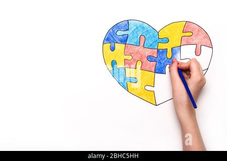 Welt Autismus Tag Bewusstsein. Die Kinderhand zieht das Herz aus bunten Puzzles. Konzept der psychischen Gesundheit. Stockfoto