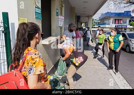 1. April 2020 - Frau, die Lebensmitteltaschen nach dem Einkaufen in einem San Salvador Supermarkt bestellt. Stockfoto