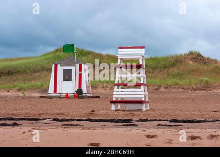 Rettungsschwimmerstation und Beobachtungsstuhl am North Rustico Beach. Grüne Flagge signalisiert ruhige Brandung. Rettungsschwimmer im Dienst, der das Wasser beobachtet. PEI, Kanada Stockfoto