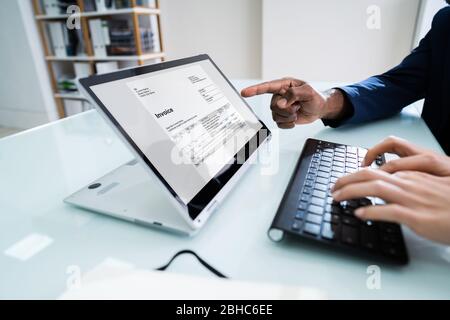 Geschäftsmann Zeigt Rechnung Auf Laptop-Bildschirm Zu Ihrem Männlichen Kollegen Während Der Arbeit Im Büro Stockfoto
