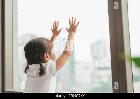 Rückansicht auf niedlichen kleinen Mädchen schaut aus dem Fenster Stockfoto