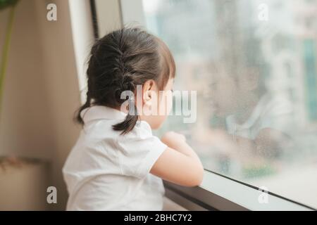 Rückansicht auf niedlichen kleinen Mädchen schaut aus dem Fenster Stockfoto