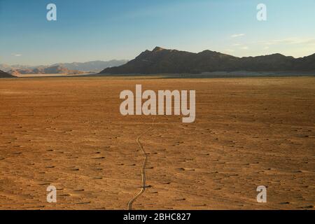 Blick auf die Piste über Ebene und Berge von oben auf einem Felsen Koppie über Desert Camp, Sesriem, Namib Wüste, Namibia, Afrika Stockfoto