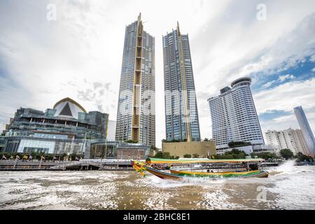 Bangkok / Thailand - 22. Juli 2019: Hochhäuser vom Chao Phraya Fluss aus gesehen in der Metropole Bangkok in Thailand. Blauer Himmel mit einigen Stockfoto