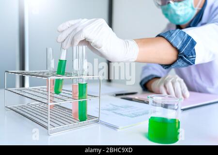 Wissenschaftler, die im Labor im weißen Labormantel recherchieren, Handschuhe analysieren, Reagenzgläser Probe betrachten, Biotechnologiekonzept. Stockfoto